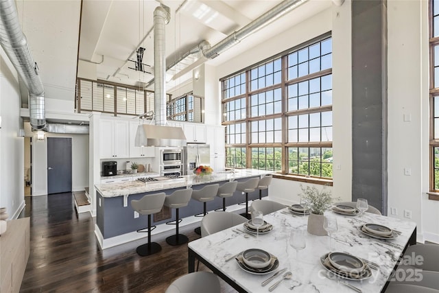 dining area with a high ceiling, dark wood-type flooring, and baseboards