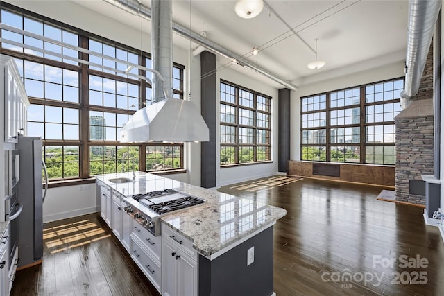 kitchen featuring appliances with stainless steel finishes, baseboards, light stone counters, dark wood-style floors, and white cabinetry