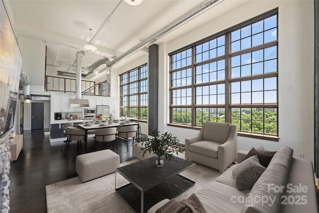 living room with a towering ceiling and dark wood-type flooring