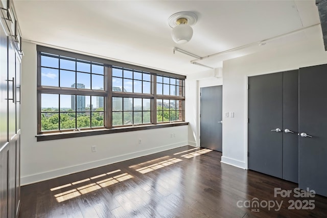 unfurnished bedroom featuring baseboards and dark wood-style floors
