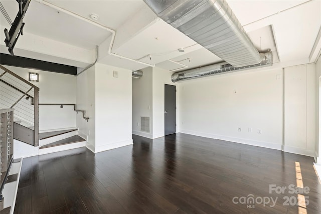 unfurnished living room with wood finished floors, baseboards, and stairway