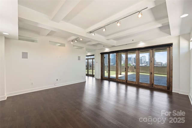 empty room featuring track lighting, dark wood-style flooring, baseboards, and beam ceiling