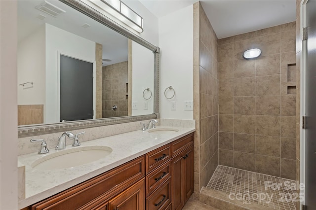 bathroom featuring tiled shower and double vanity