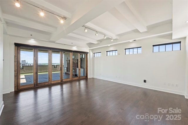 unfurnished room featuring track lighting, beam ceiling, dark wood-style flooring, and plenty of natural light