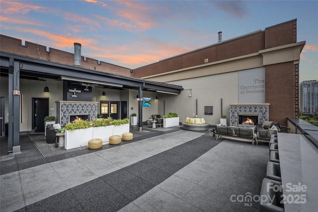 rear view of house with a patio area, an outdoor living space with a fireplace, and stucco siding