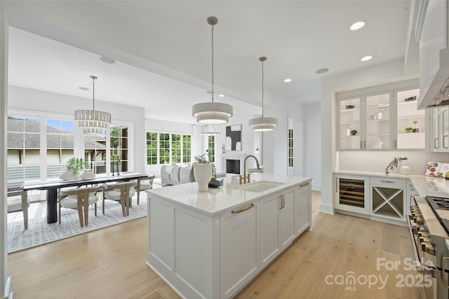 536 Hillside Ave, Charlotte, NC 28209 - kitchen with beverage cooler, a sink, double oven range, white cabinets, and light wood-style floors