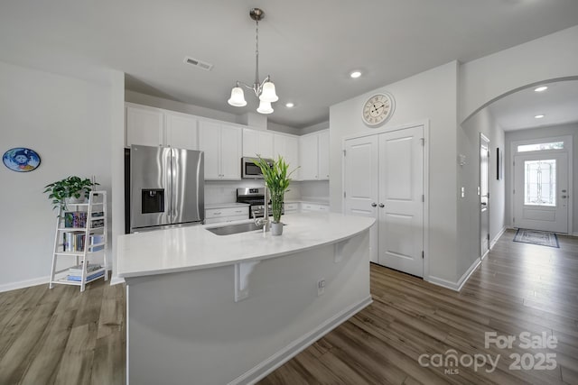 5034 Moss Pine Way, Tega Cay, SC 29708 - kitchen with appliances with stainless steel finishes, dark wood-style floors, arched walkways, white cabinets, and recessed lighting