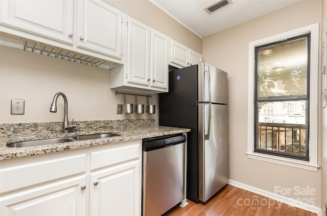 216 S Clarkson St Unit E, Charlotte, NC 28202 - kitchen featuring appliances with stainless steel finishes, a sink, light wood finished floors, white cabinetry, and baseboards