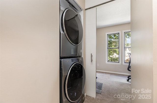 216 S Clarkson St Unit E, Charlotte, NC 28202 - laundry room featuring stacked washing machine and dryer, carpet flooring, and baseboards