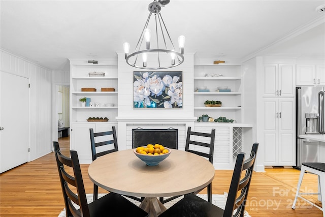 5162 Lincrest Pl, Charlotte, NC 28211 - dining space featuring light wood finished floors, ornamental molding, a chandelier, a fireplace, and built in features