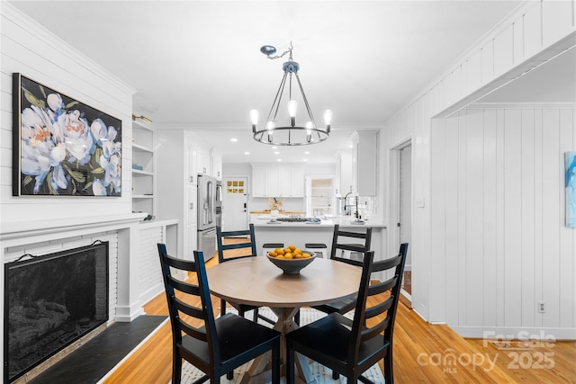 5162 Lincrest Pl, Charlotte, NC 28211 - dining area featuring a chandelier, light wood-style floors, ornamental molding, a fireplace with flush hearth, and recessed lighting