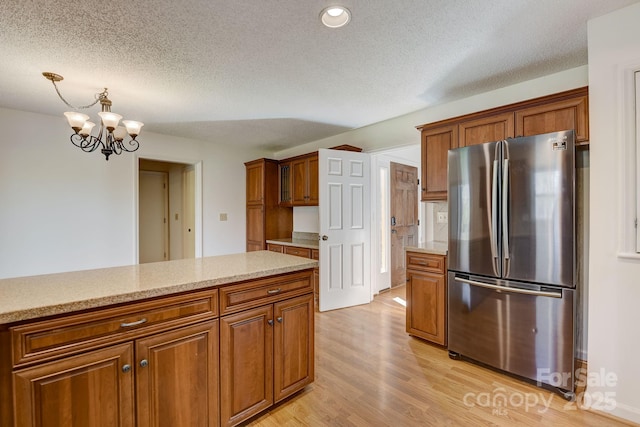 5108 Tedorill Ln, Charlotte, NC 28226 - kitchen featuring freestanding refrigerator, brown cabinetry, light wood-style flooring, a chandelier, and a textured ceiling