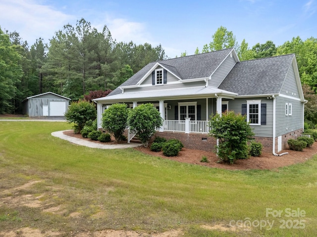 view of front of property featuring a garage, a porch, a shingled roof, a front yard, and an outdoor structure