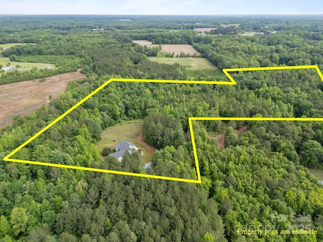 aerial view of property and surrounding area featuring a heavily wooded area and property boundaries highlighted