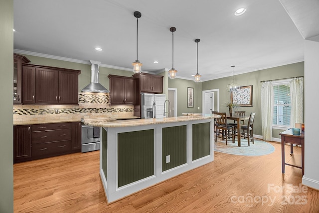 kitchen featuring wall chimney range hood, stainless steel appliances, dark brown cabinets, decorative backsplash, and recessed lighting