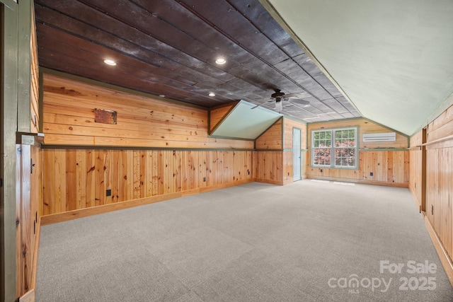 bonus room featuring wood walls, carpet, a wall mounted air conditioner, lofted ceiling, and ceiling fan