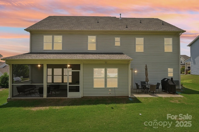 3218 Gilroy Dr, Fort Mill, SC 29707 - back of property at dusk with a patio area, a yard, a shingled roof, and a sunroom