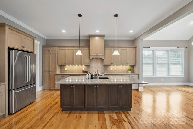 kitchen featuring high end fridge, light wood-style flooring, light stone countertops, backsplash, and crown molding