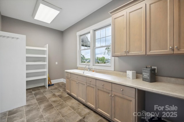 kitchen featuring a sink, light countertops, and baseboards