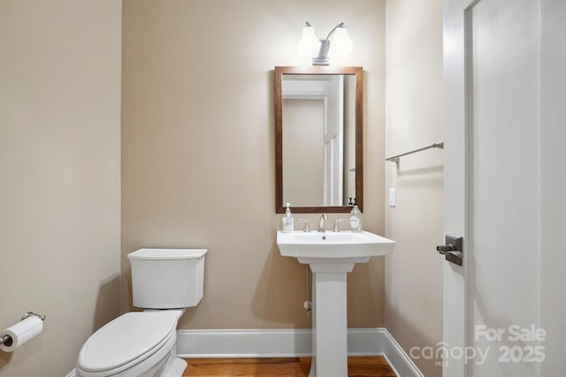 bathroom featuring toilet, baseboards, and wood finished floors
