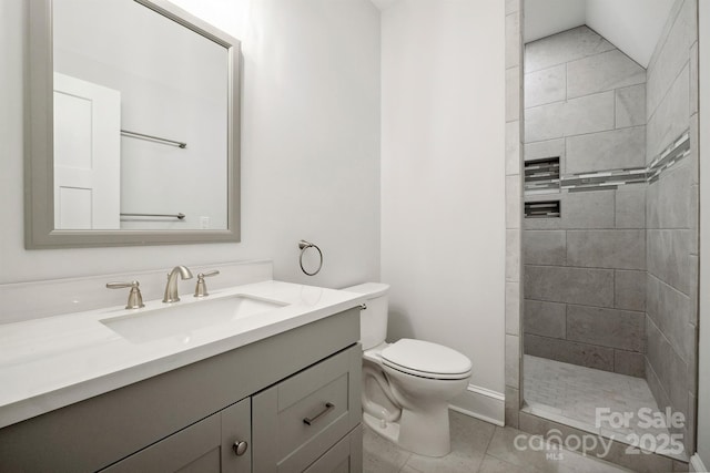 bathroom featuring vanity, a tile shower, toilet, and tile patterned floors