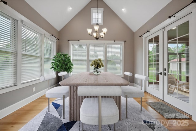 dining space featuring light wood-style flooring, a chandelier, high vaulted ceiling, french doors, and baseboards