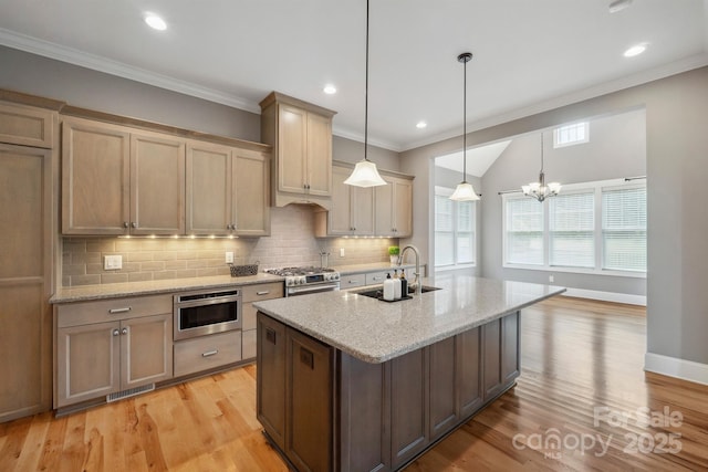 kitchen featuring stainless steel gas range, a sink, decorative backsplash, light wood-type flooring, and an island with sink
