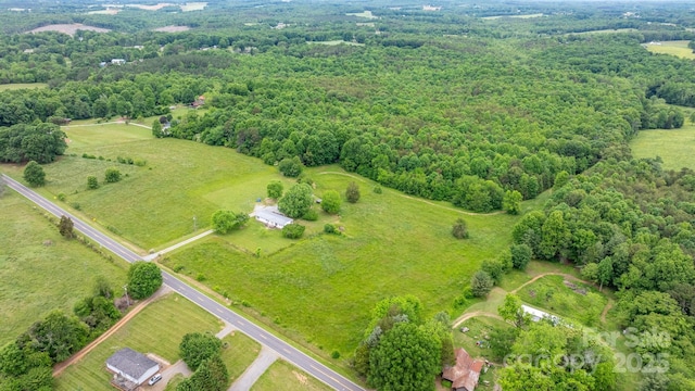 aerial view of property and surrounding area featuring a heavily wooded area