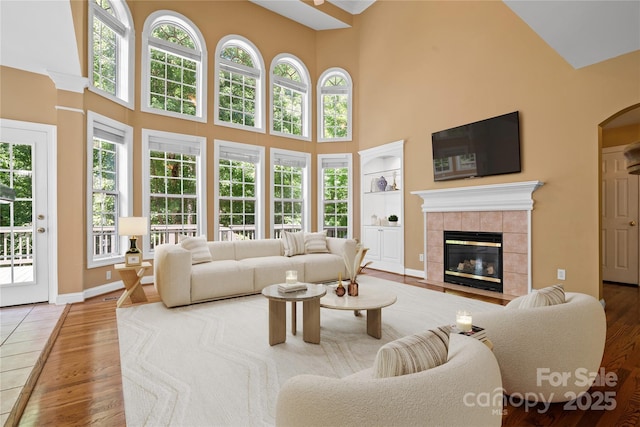 10616 Back Ridge Rd, Charlotte, NC 28277 - living area with a high ceiling, a tiled fireplace, wood finished floors, arched walkways, and built in shelves