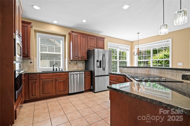 10616 Back Ridge Rd, Charlotte, NC 28277 - kitchen featuring stainless steel appliances, a sink, tasteful backsplash, hanging light fixtures, and dark stone countertops