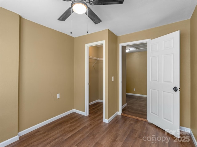 280 Noland Dr, Clyde, NC 28721 - unfurnished bedroom featuring dark wood-type flooring, a walk in closet, a closet, baseboards, and a ceiling fan