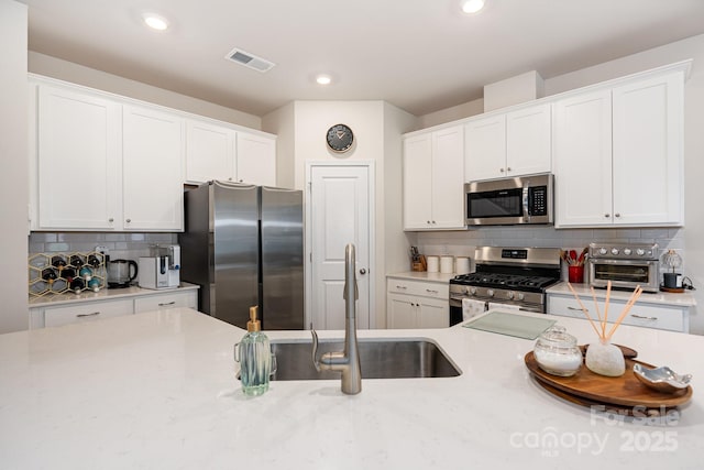 6011 Chelsea Oaks Rdg, Tega Cay, SC 29708 - kitchen featuring stainless steel appliances, a sink, light countertops, tasteful backsplash, and white cabinets