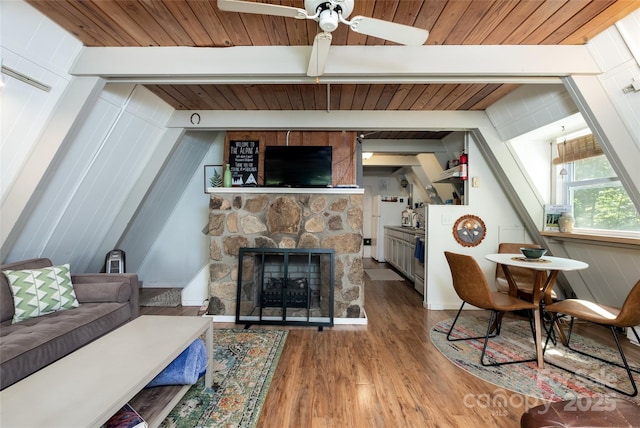 living area featuring wooden ceiling, wood finished floors, a ceiling fan, a fireplace, and beam ceiling