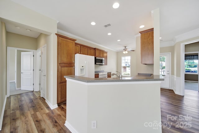 28129 Song Sparrow Ln, Fort Mill, SC 29707 - kitchen with white appliances, dark wood finished floors, brown cabinets, ornamental molding, and recessed lighting