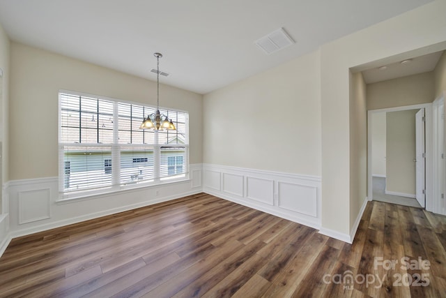 28129 Song Sparrow Ln, Fort Mill, SC 29707 - unfurnished dining area featuring dark wood-style floors, a chandelier, a wainscoted wall, and a decorative wall