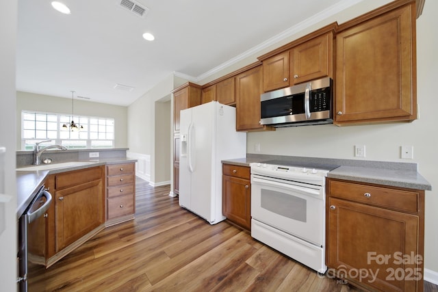 28129 Song Sparrow Ln, Fort Mill, SC 29707 - kitchen with stainless steel appliances, a sink, brown cabinets, light wood-type flooring, and a chandelier