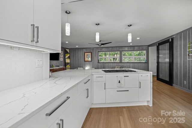 2121 Valencia Ter, Charlotte, NC 28226 - kitchen featuring cooktop, ceiling fan, white cabinets, light wood-style flooring, and a peninsula