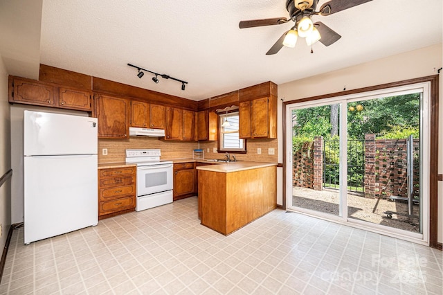 1330 5th St NE Unit 145, Hickory, NC 28601 - kitchen with white appliances, brown cabinetry, under cabinet range hood, light countertops, and a peninsula