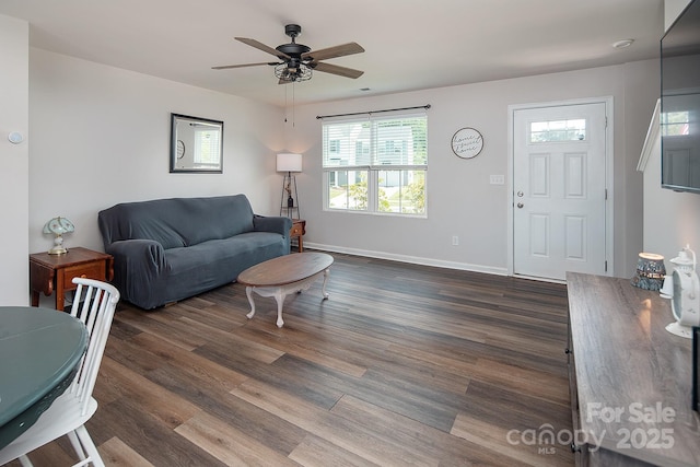 living area featuring dark wood-style flooring, a ceiling fan, and baseboards