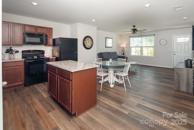 kitchen featuring black appliances, open floor plan, dark wood-type flooring, ceiling fan, and a center island