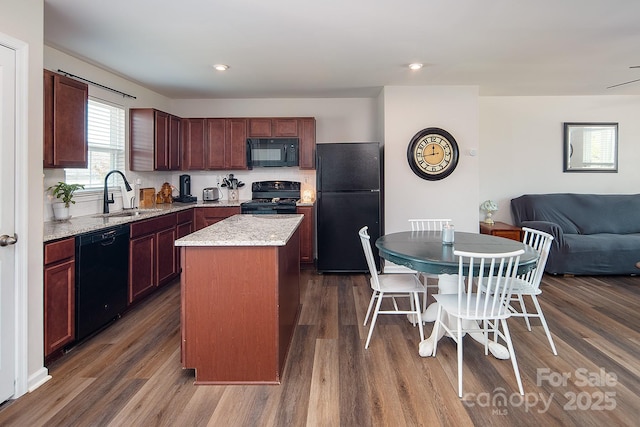 kitchen with black appliances, a sink, dark wood-type flooring, a kitchen island, and open floor plan