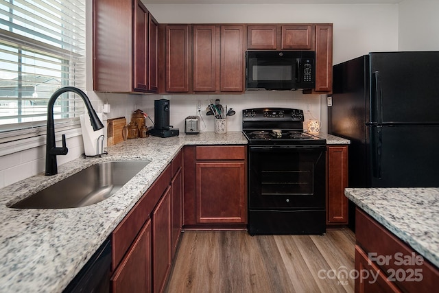 kitchen featuring black appliances, a sink, backsplash, and wood finished floors