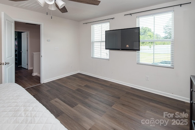 unfurnished bedroom featuring dark wood-style floors, baseboards, and multiple windows