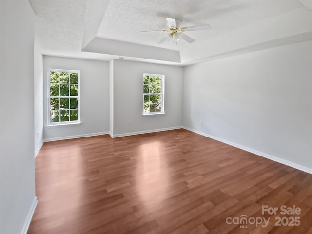 1184 Lempster Dr NW, Concord, NC 28027 - empty room with a raised ceiling, wood finished floors, a ceiling fan, and baseboards