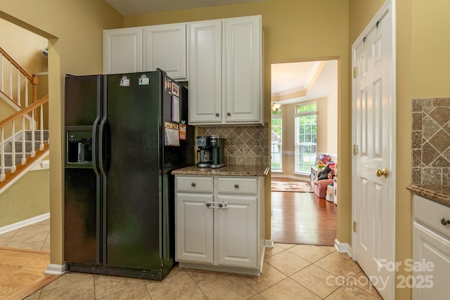 5656 Cambridge Bay Dr, Charlotte, NC 28269 - kitchen with black refrigerator with ice dispenser, white cabinets, backsplash, light tile patterned floors, and baseboards