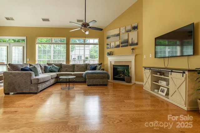 5656 Cambridge Bay Dr, Charlotte, NC 28269 - living room featuring wood finished floors, ceiling fan, vaulted ceiling, healthy amount of natural light, and a glass covered fireplace