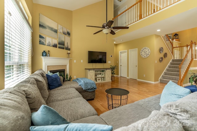 5656 Cambridge Bay Dr, Charlotte, NC 28269 - living area featuring stairway, a glass covered fireplace, wood finished floors, a ceiling fan, and baseboards