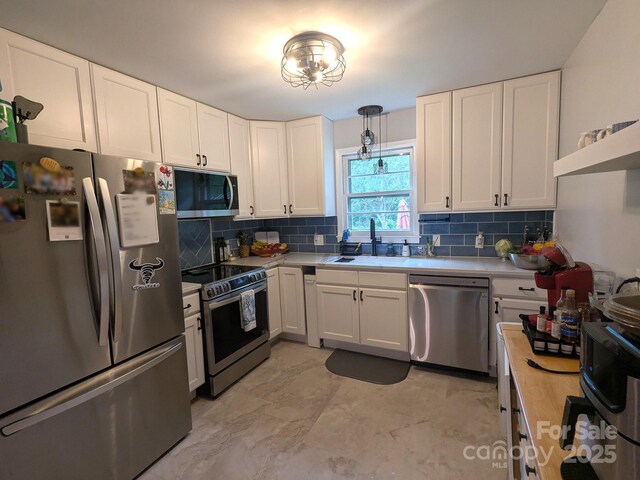 3116 Pilgrim Rd, Chester, SC 29706 - kitchen with appliances with stainless steel finishes, white cabinetry, a sink, tasteful backsplash, and pendant lighting