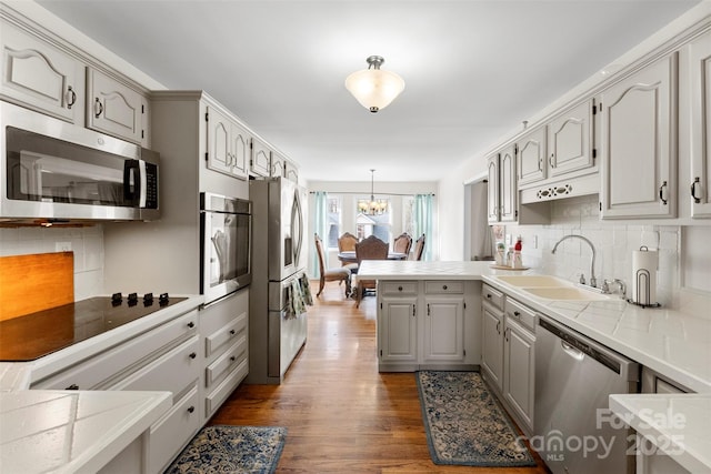 148 Fairway Dr, Forest City, NC 28043 - kitchen featuring stainless steel appliances, a peninsula, a sink, a chandelier, and wood finished floors