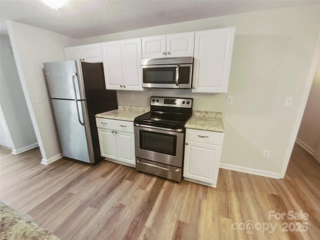 kitchen with stainless steel appliances, light wood finished floors, white cabinetry, and baseboards